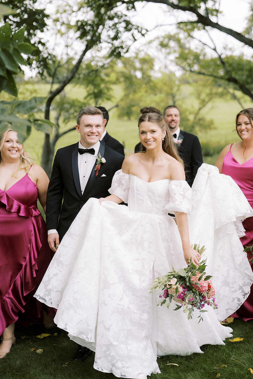 Bride and groom walking with bridal party outdoors